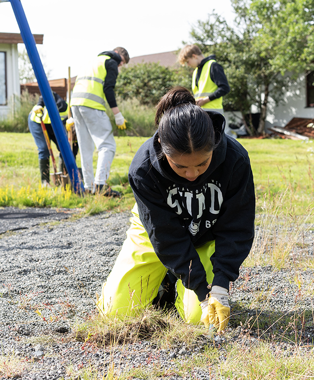 Unglingar vinna við hreinsun á leikvelli í Vinnuskólanum.