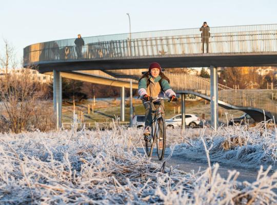 A cyclist passes under a pedestrian and bicycle bridge on a cold day in Reykjavík.