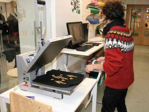 Kona þrykkir grafík á taupoka.