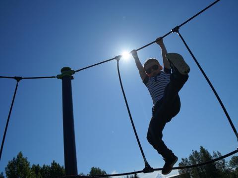 Drengur í klifurgrind á sólardegi