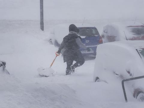 Kona að brjótast í gegnum skafl með skóflu í hendi.