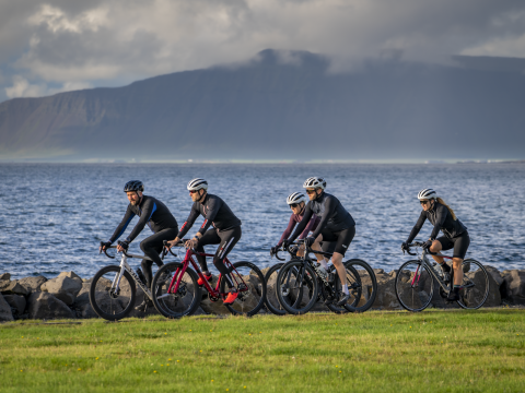 Fólk á hjóli á stíg við sjóinn. Esjan í bakgrunni.