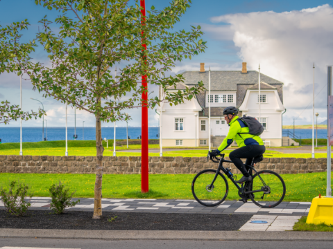 Reiðhjólamaður hjólar á hjólastíg í Borgartúni með Höfða í baksýn.