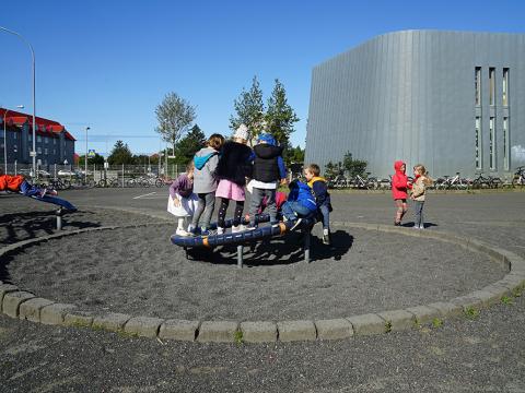 Children on playground equipment at Melaskóli grounds.