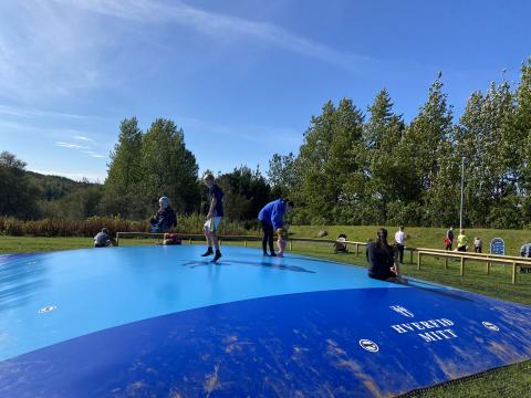 Hoppandi börn og fullorðnir á ærslabelg í Árbæ.