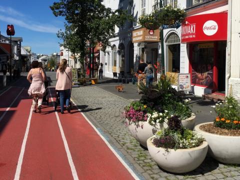 Fólk á göngu niður Laugaveg á sólríkum degi.