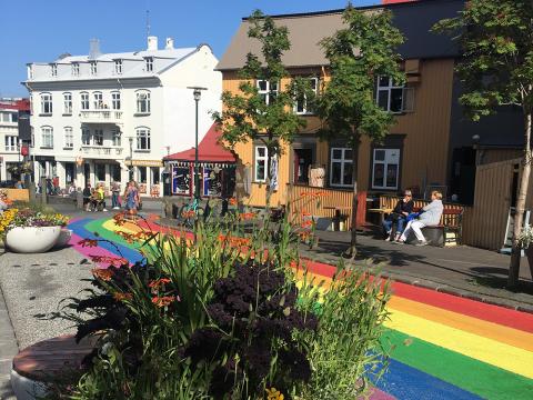 Fólk á regnbogamáluðum Skólavörðustíg á sólríkum degi.