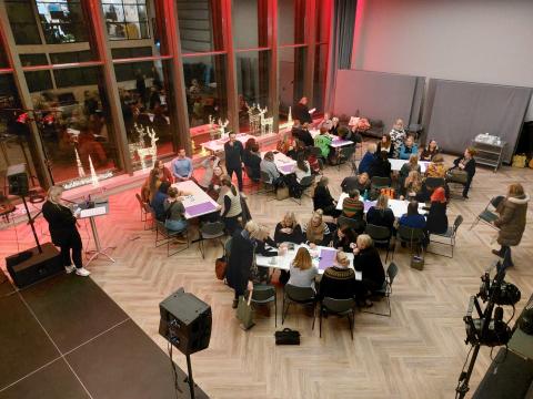 Stjórnendur leikskóla sitja í stórum sal á vinnustofu um innritunarferli í leikskóla. Jólaskreytingar í gluggum. Myndin er tekin ofan frá.