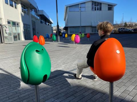 Drengur situr í túlípanasæti á torgi í Mjódd.