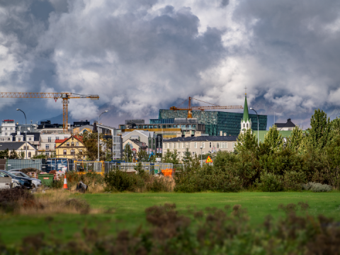 Byggingarkranar, grænt svæði og hús í Reykjavík.