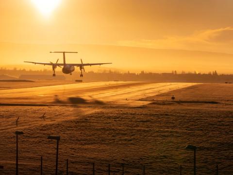 Flugvél lendir í Vatnsmýri. Gul birta, vetrarsól, kalt og stilla.