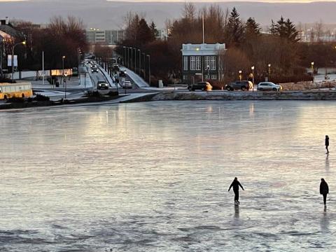 Ljósmynd af frosinni Tjörn og umferð á Skothúsvegi og Sóleyjargötu.