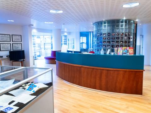 Mynd tekin innan í Borgarskjalasafni. Sýnir bogadregið borð, í forgrunni glærir kassar með sýningarskjölum.