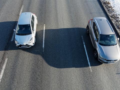 Tveir bílar að keyra á götu, horft ofan á þá og þeir eru að keyra "að" áhorfandanum.