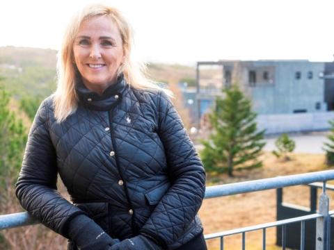 Heiða Björk Júlíusdóttir situr í íbúaráði Grafarholts og Úlfarsárdals. Hér er hún á svölunum sínum, í úlpu og hönskum, hallar sér upp að svaragrindverki með hverfið og náttúruna í bakgrunni.