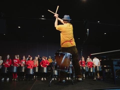 Baksvipur á trommara með börn fyrir framan sig, frá Big bang í Hörpu