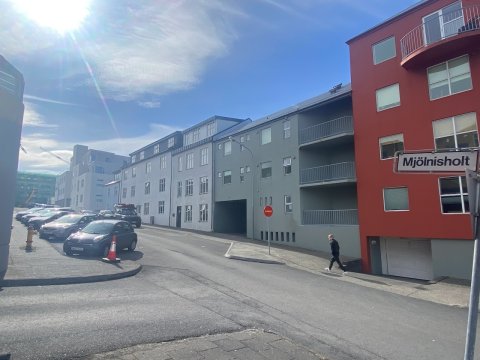 Auð gata og hús. Nokkrum bílum lagt við götuna.