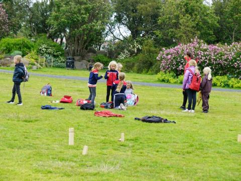 Börn spila kubb á túni í sumarfrístund.