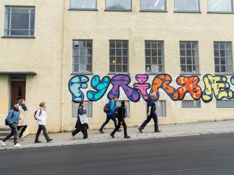 Fólk gengur framhjá vegglistaverki við Ægisgötu 7.