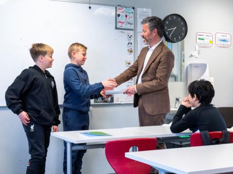 Dagur B. Eggertsson borgarstjóri veitir viðtöku undirskriftalista frá börnum í Landakotsskóla. Á myndinni tekur hann í hönd annars drengjanna sem stóðu að listanum, hinn fylgist með ásamt einu barni enn, sem situr. Mynd úr skólastofu.