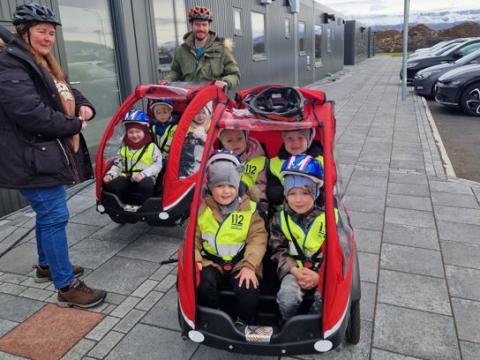 Börn á leikskólanum Hálsaskógi í tveimur rafhjólum. Tveir kennarar með á myndinni.