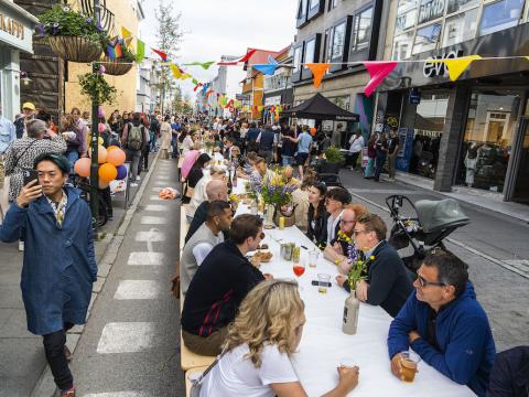 People sit at long tables on Laugavegur pedestrian street.