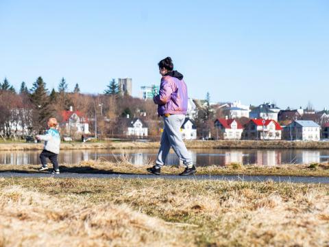 Foreldri og barn á gangi við Tjörnina.