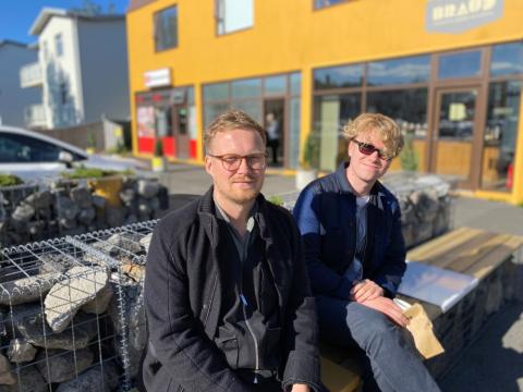 Tveir menn sitja á bekk fyrir utan Brauð & Co við Laugalæk.