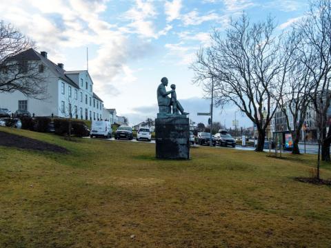 Minnismerki um séra Friðrik við Lækjargötu. Víð mynd, horft á hlið styttunnar úr nokkurri fjarlægð, í átt að MR.