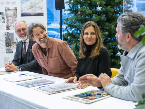 Fólk að skrifa undir samning við borð. Jólatré í baksýn.