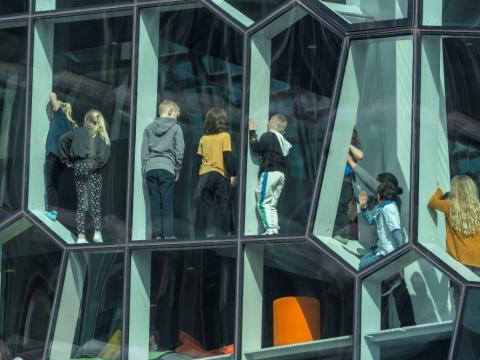 Mynd tekin inn um glugga á Hörpu, sést aftan á nokkur börn sem standa í gluggunum.