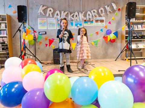 Tvö börn syngja í krakkarokki í Ævintýrahöllinni 2023, barnamenningarhátíð, blöðrur í forgrunni.