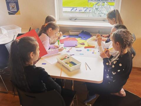 Sex börn sitja við borð og föndra