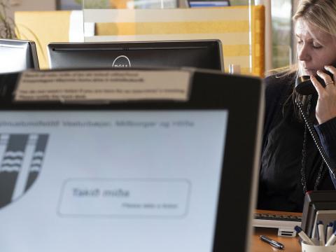Ráðgjafi á velferðarsviði talar í síma, tölvuskjár í forgrunni. 