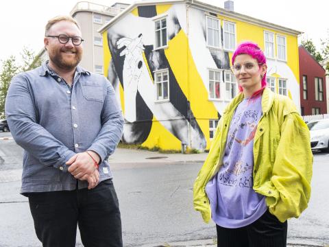 Adam Flint Taylor, program director of graphic design, and artist Natka Klimowicz stand in front of Andrými, featuring a mural.