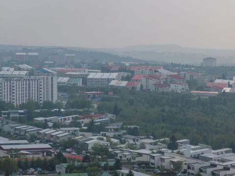 View over houses and trees with mist in the air.