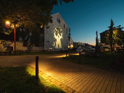 garður með gangstétt, vegglistaverki og fallegri lýsingu