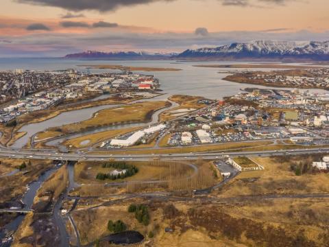 Loftmynd yfir Geirsnef sem sýnir veg, gras, hús, sjó og ár.