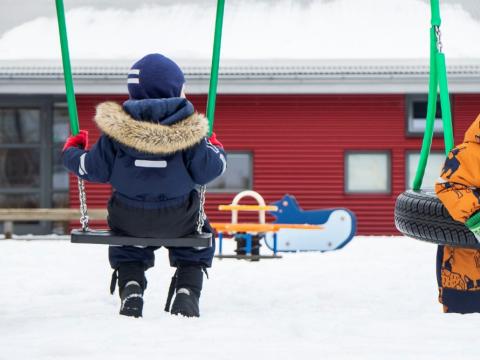 Children in swings at a preschool.