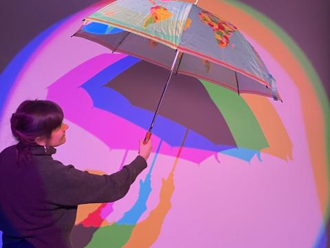 Students explore artistic expression using colors and an umbrella.
