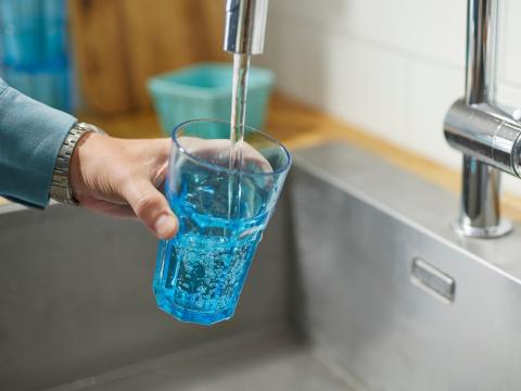 Water flowing from a tap into a glass held under the stream