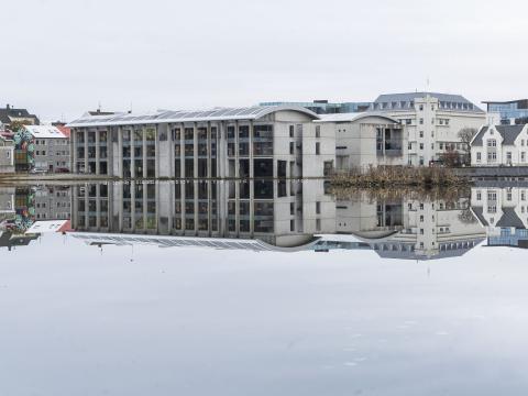 Ráðhús og húsin í kring speglast í spegilsléttri Tjörninni