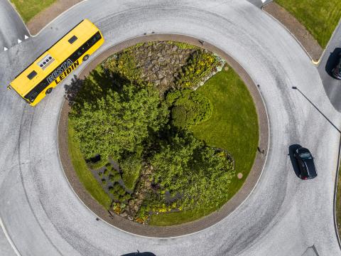 Aerial photo of a Strætó Public Transport bus driving around a lush roundabout.