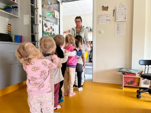 Leikskólabörn í röð og kennari tekur á móti þeim