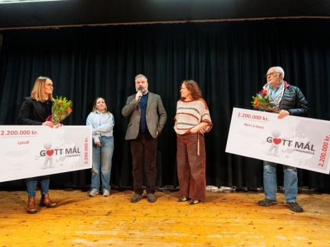 Fimm einstaklingar á sviði með tvær stórar ávísanir