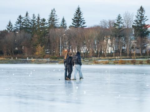 Þrír unglingar ganga yfir frosna Tjörnina í Reykjavík