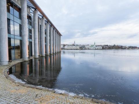 Ráðhúsið, sjónarhorn frá Tjarnargötu. Fyrir miðju má sjá Fríkirkjuna og Hallgrímskirkju, Tjörnin í forgrunni, Ráðhúsið til vinstri. Logn.