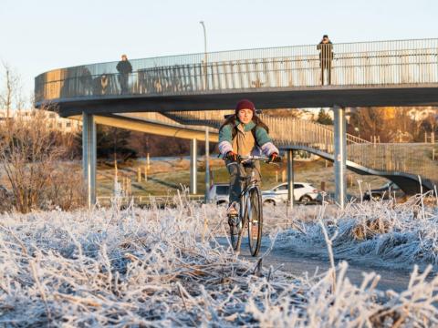 A cyclist passes under a pedestrian and bicycle bridge on a cold day in Reykjavík.