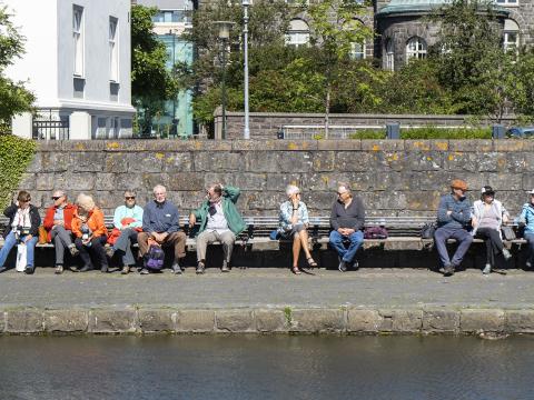 Hópur af eldra fólki situr við Tjörnina í Reykjavík