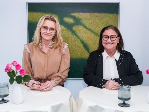 Inga Sæland, mennta- og barnamálaráðherra og Heiða Björg Hilmisdóttir borgarstjóri í Reykjavík undirrita samning um að styðja við og auka aðgengi barna og ungmenna á aldrinum 16–25 ára að skipulögðu frístunda- og félagsstarfi í Breiðholti. Heiða til vinstri, Inga til hægri, málverk í bakgrunni. Standa við borð.